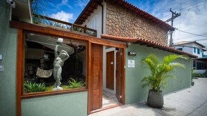 A building with a stone facade, a wooden door, and a potted plant outside. - Bella Buzios Apartamentos (Búzios)