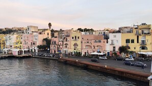 Un paysage urbain au bord de l’eau, avec des bâtiments aux couleurs vives, un quai où sont amarrés des bateaux et une promenade piétonne.