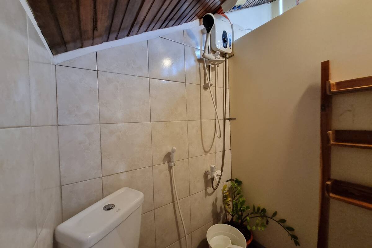 Een badkamer met toilet, douche en plafondventilator.