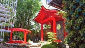 A traditional Japanese structure with a red roof, surrounded by greenery and rocks. - Orokasa Guesthouse (Puerto Princesa)