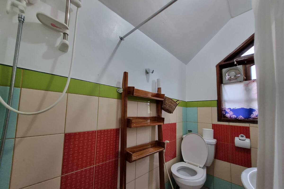 Een badkamer met een toilet, douche en een plank met een mandje.