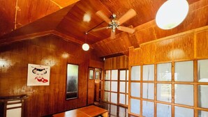 A traditional Japanese-style room with wooden walls, tatami flooring, a ceiling fan, and sliding shoji doors. - Orokasa Guesthouse (Puerto Princesa)