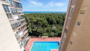 A high-rise building with a rooftop pool overlooking a forested area and the sea. - Apartamento Lake & SEA (Valencia)