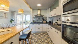 A modern kitchen with a wooden dining table, white cabinets, and a large oven. - Apartamento Lake & SEA (Valencia)