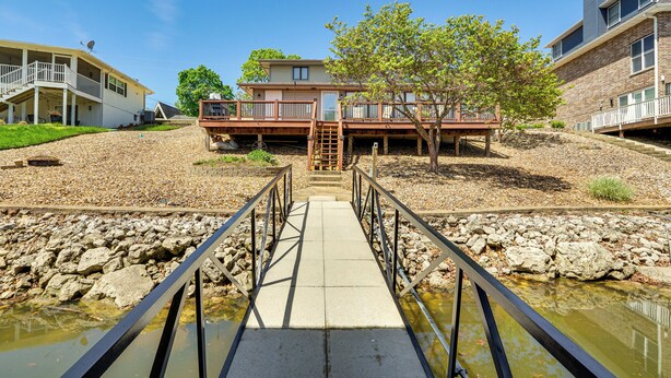 A bridge leading to a house with a deck and a tree. - Private Dock & Deck: Waterfront Camdenton Home! (Camdenton)