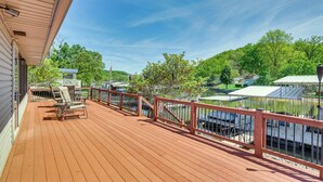 A wooden deck with a railing, overlooking a body of water and greenery. - Private Dock & Deck: Waterfront Camdenton Home! (Camdenton)