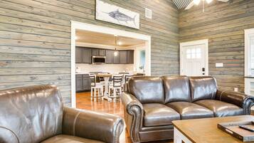 A spacious living area with leather sofas, a wooden coffee table, and a ceiling fan.