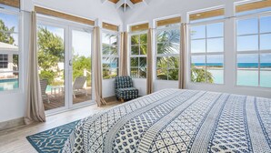 A spacious bedroom with a large bed, multiple windows, and a view of the ocean. - BEACHFRONT! Best Location on Private Lazy River Sand Bar.  Always Calm Water! (Moore Hill)