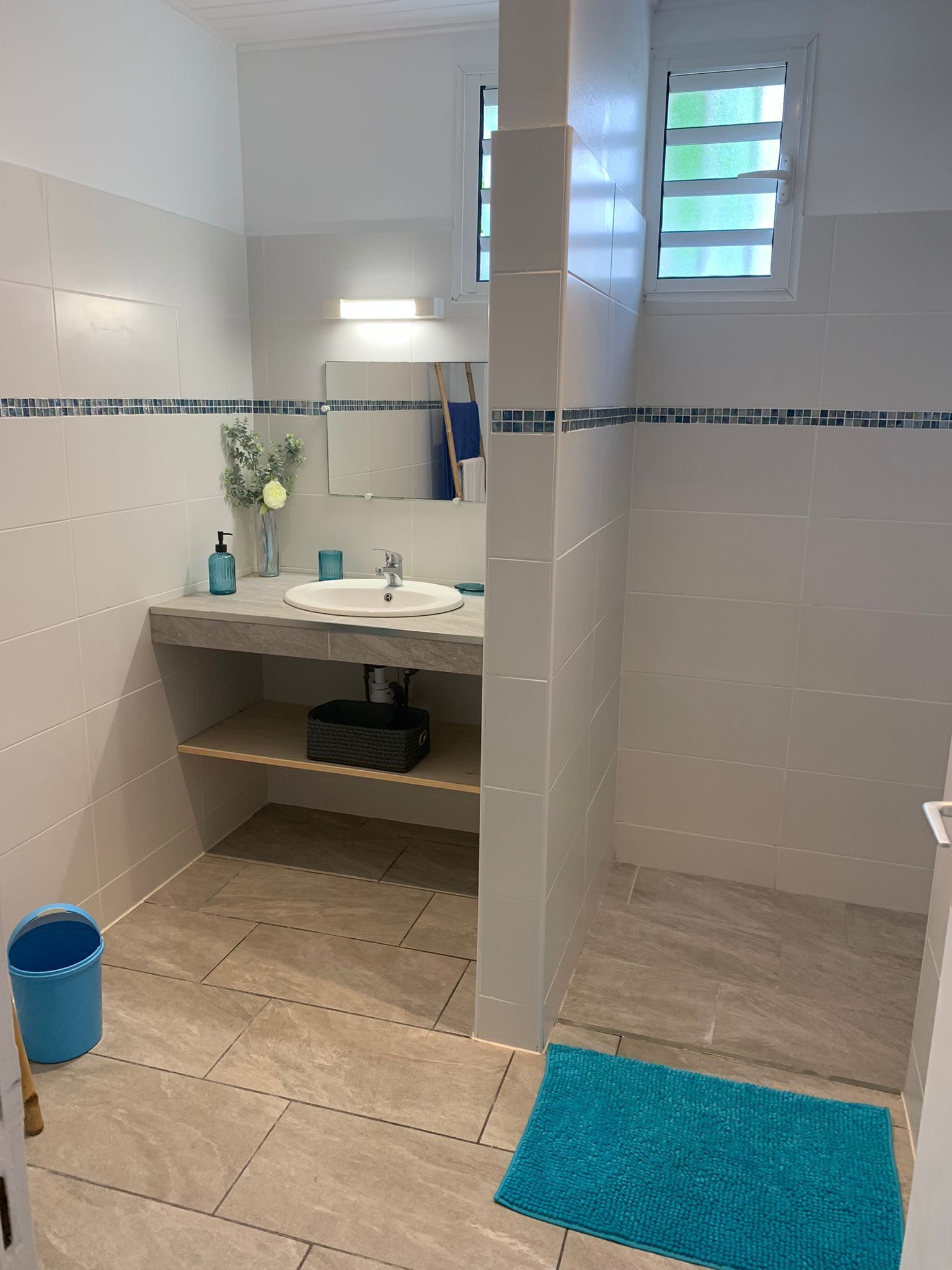 A bathroom with a sink, mirror, and a small window.