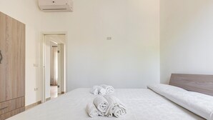 A hotel room with a neatly made bed, a wooden wardrobe, and a door leading to another room. - 3882 Residenza Virginia by Barbarhouse (Tricase)