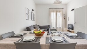 A dining area with a table set for four, a basket of fruit, and a television in the background. - 3882 Residenza Virginia by Barbarhouse (Tricase)