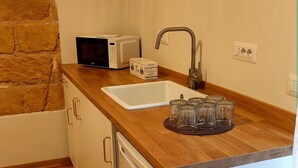 Una cocina compacta con encimera de madera, un lavamanos blanco, un microondas y un mueble pequeño.