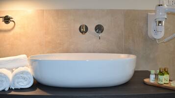 A bathroom with a large white sink, two wall-mounted towel dispensers, and a wall-mounted hairdryer.