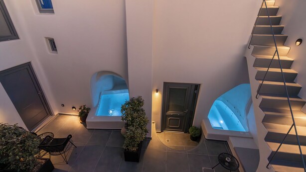 A modern interior with a staircase, a small seating area, and a door leading to a room with a bathtub. - Alaya Suites (Pyrgos)