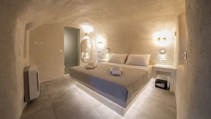 A bedroom with a bed, bedside tables, a mirror, and wall-mounted lights. - Alaya Suites (Pyrgos)