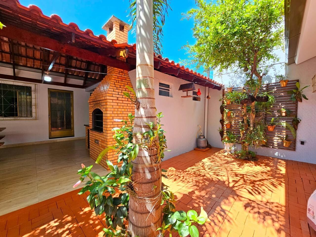 A courtyard with a brick oven, potted plants, and a tiled floor.