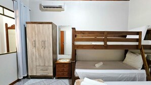 Un dormitorio con una cama litera, un armario, una mesita de noche y un espejo.