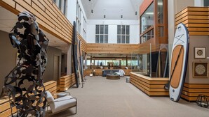 Un vestíbulo amplio con techo alto, detalles de madera y una zona de estar con una mesita de café.