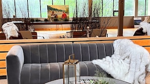 A modern living room with a grey sofa, a round coffee table with a lantern, and a white fluffy throw.