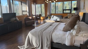 A spacious bedroom with a large bed, a television, and a desk.