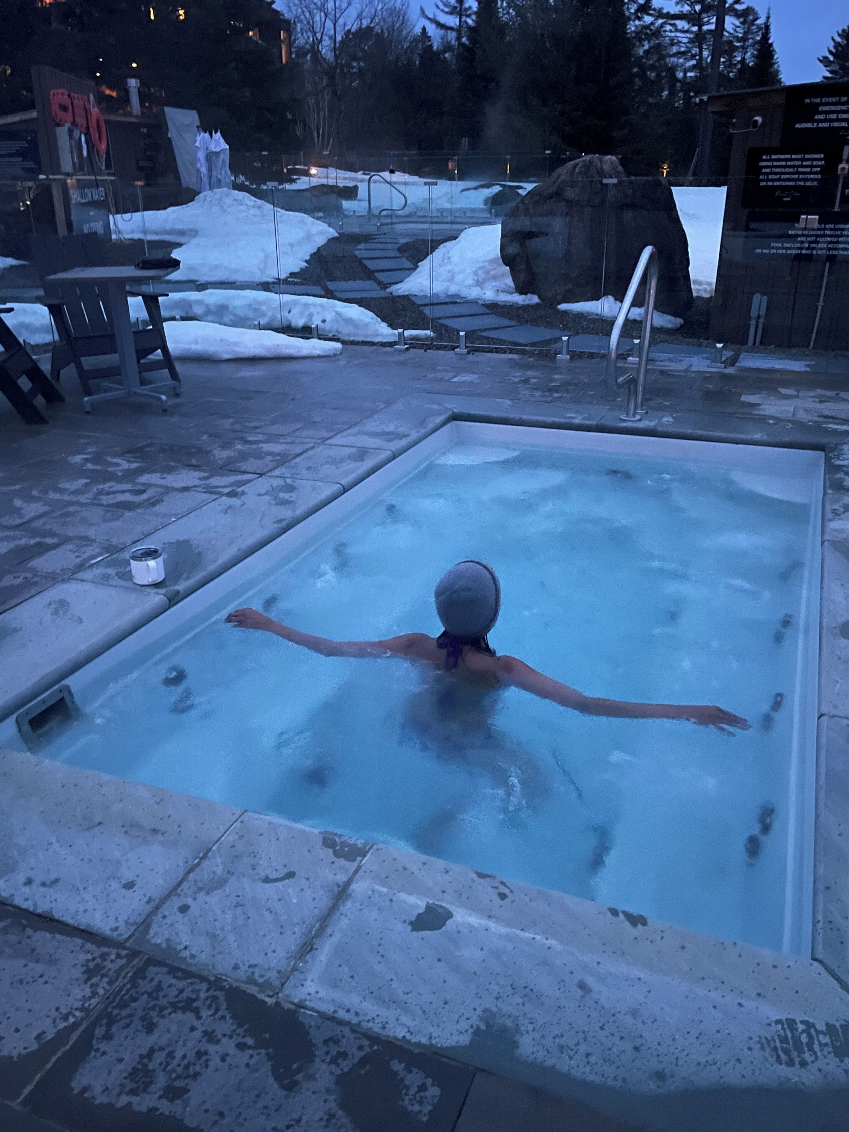 A person in a hot tub with a snowy landscape in the background.