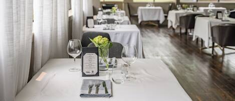 A dining area with tables set for a meal, including menus and wine glasses.