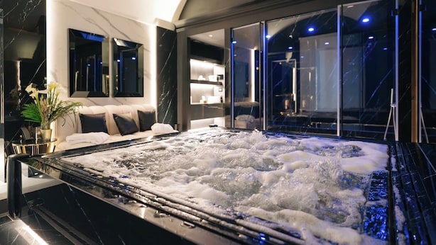 A modern spa room with a hot tub, a sofa, and a large mirror. - Bra Hotel Bari (Bari)