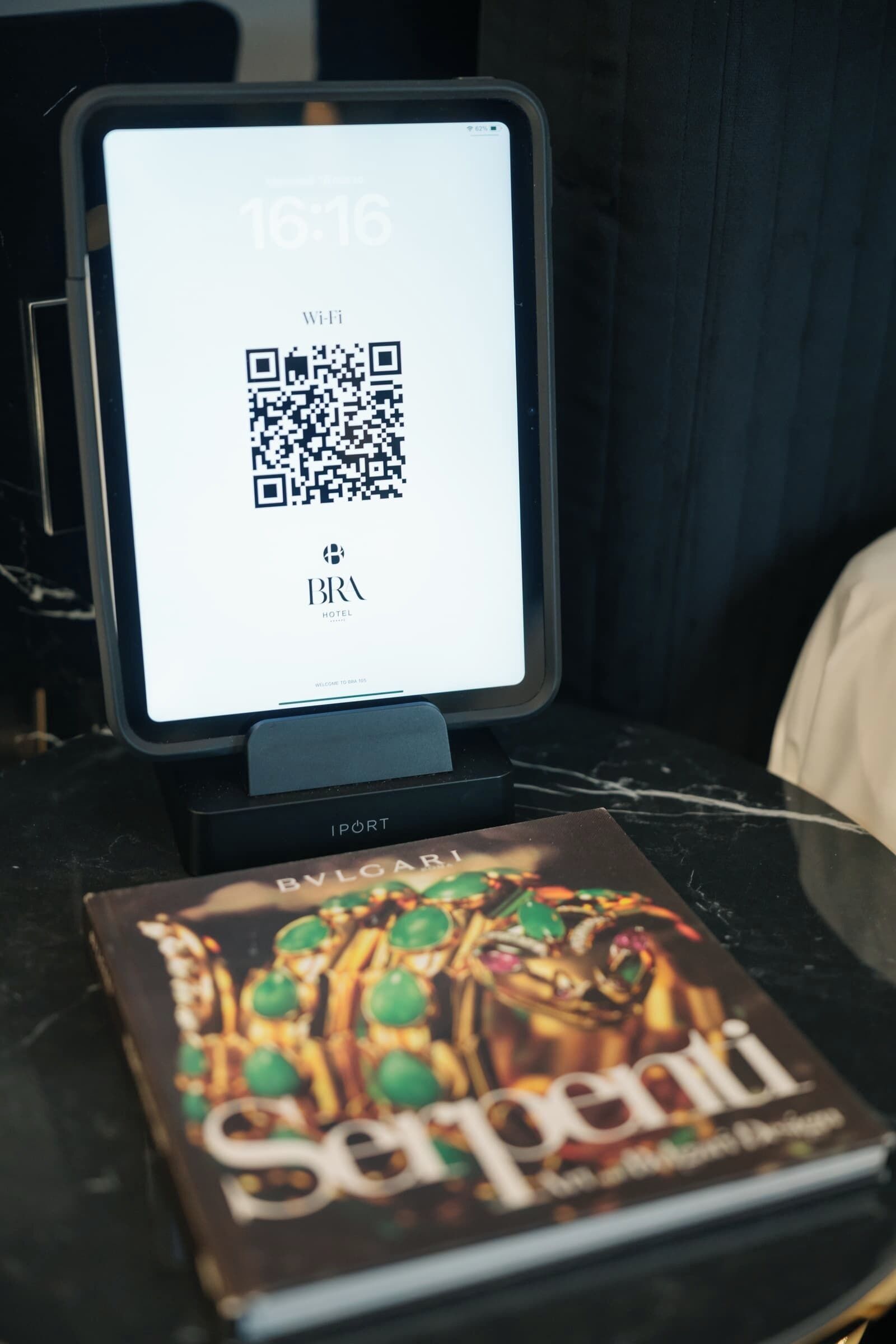 Una tableta que muestra un código QR, el nombre de un hotel y la hora de las 16:16.
