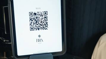 Una tableta que muestra un código QR, el nombre de un hotel y la hora de las 16:16.