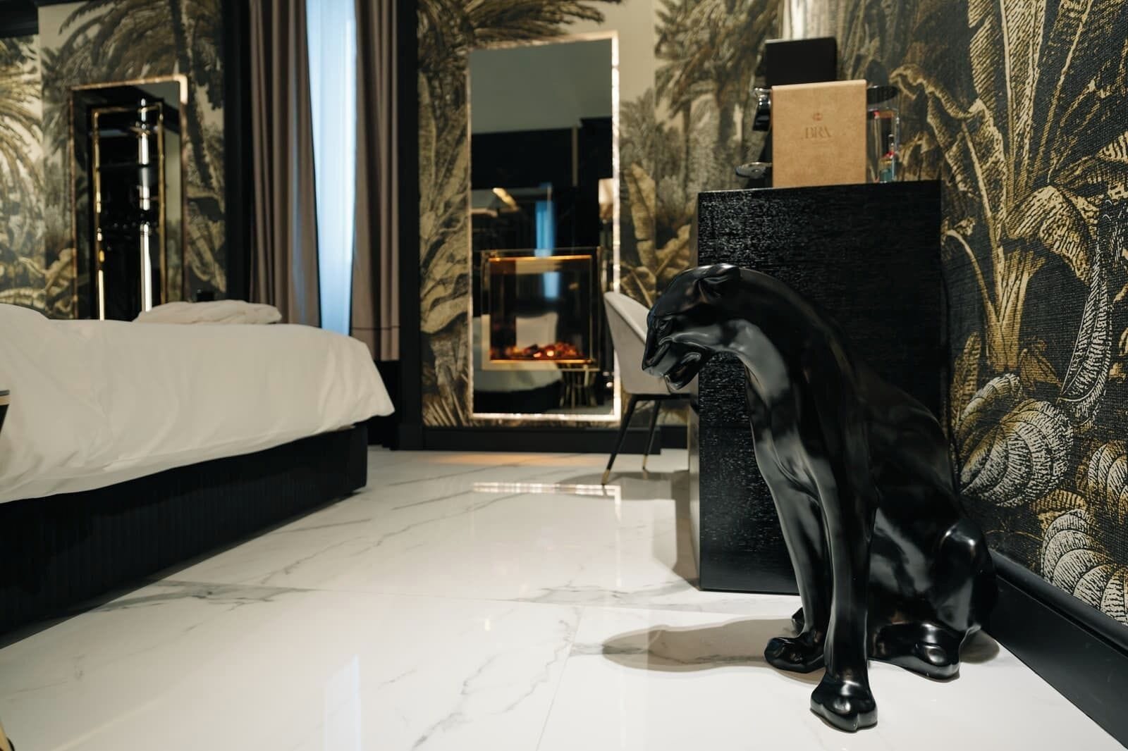 Un dormitorio moderno con una cama, una escultura negra y un espejo.