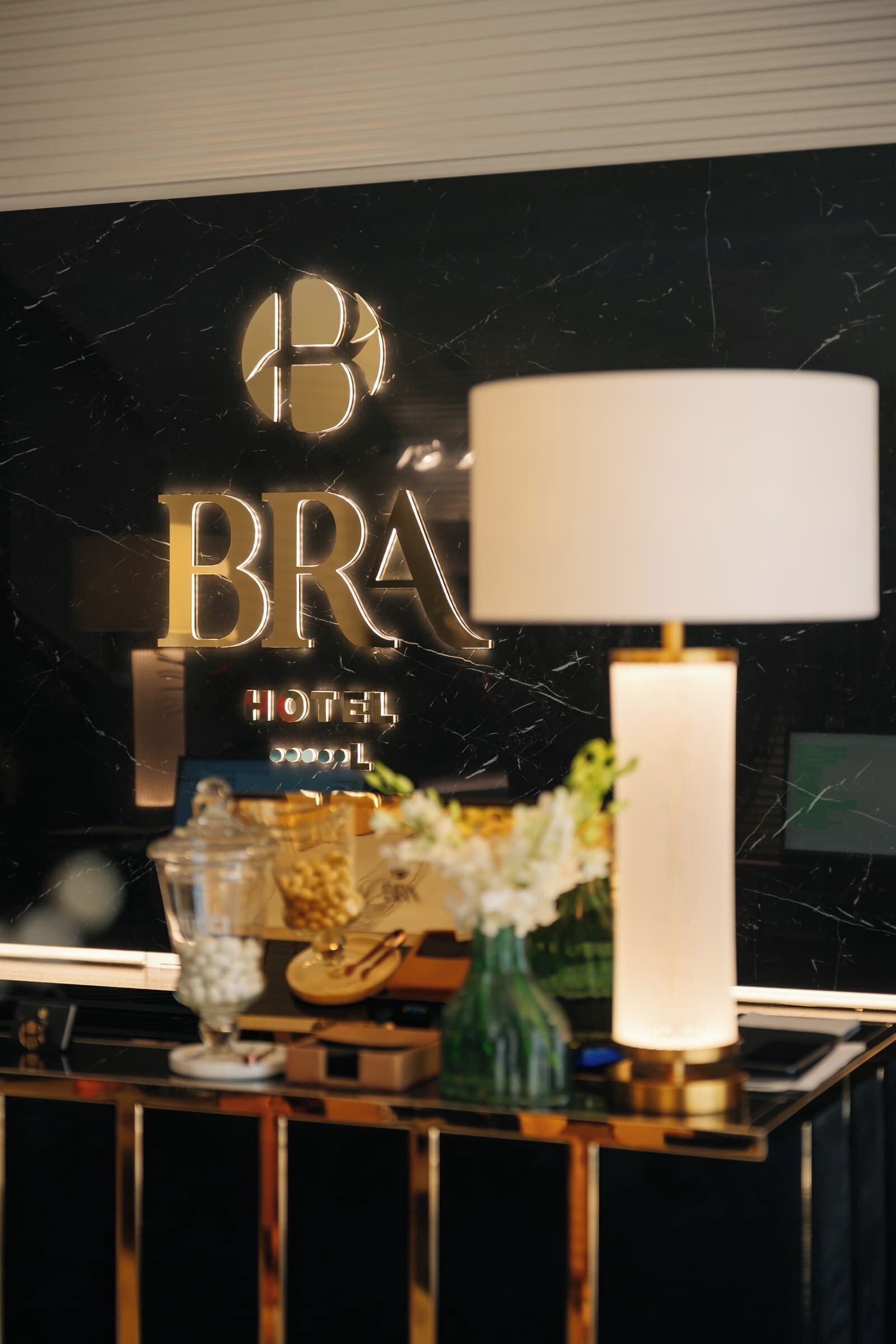 Et hotelskilt med logo og teksten 'BRÁ HOTEL' på en marmorvæg.