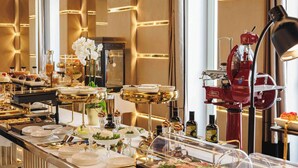 A buffet setup with various food items, a coffee machine, and a decorative plant. - Bra Hotel Bari (Bari)