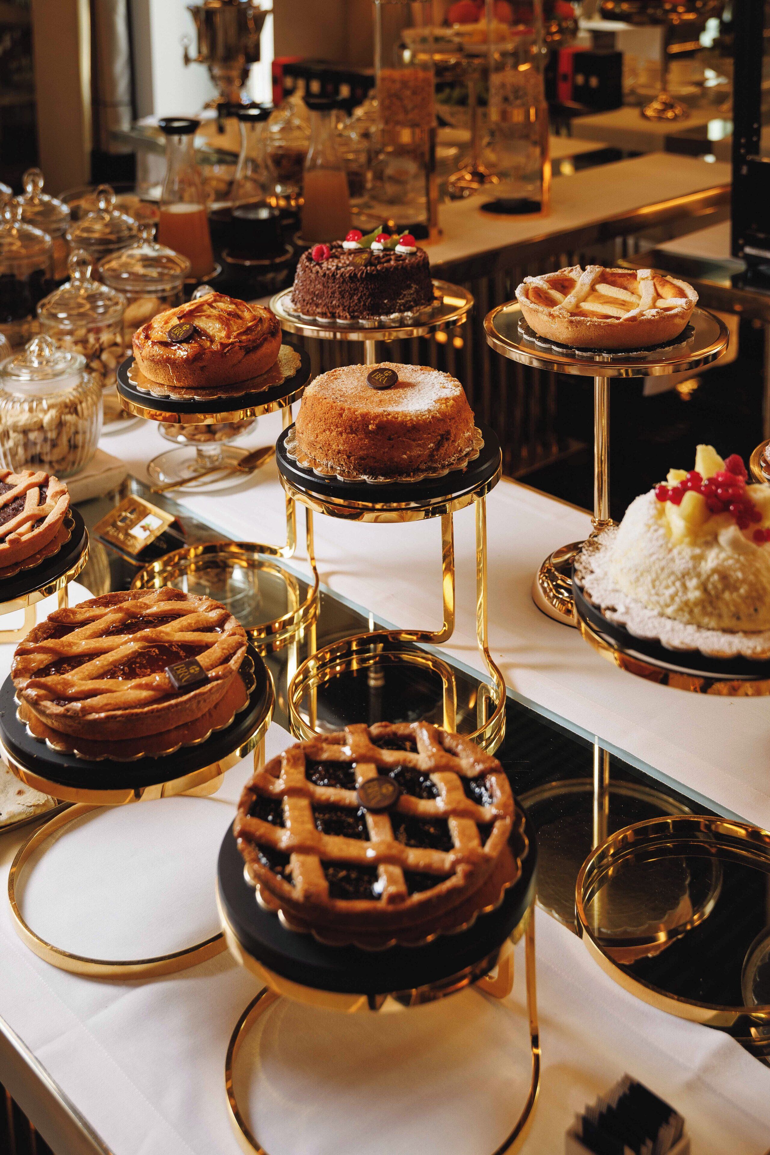 A variety of desserts displayed on a table with glass stands and gold accents.