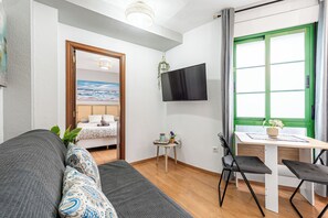 Une chambre moderne équipée d’un lit, d’un bureau avec une chaise, d’une télévision et d’une fenêtre avec des rideaux.