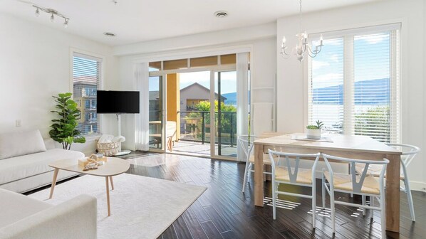 Una sala de estar moderna con sofá, mesa de centro y comedor con mesa y sillas.