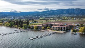 Vue aérienne d’une propriété au bord du lac, comprenant plusieurs bâtiments, des bateaux amarrés et une marina.