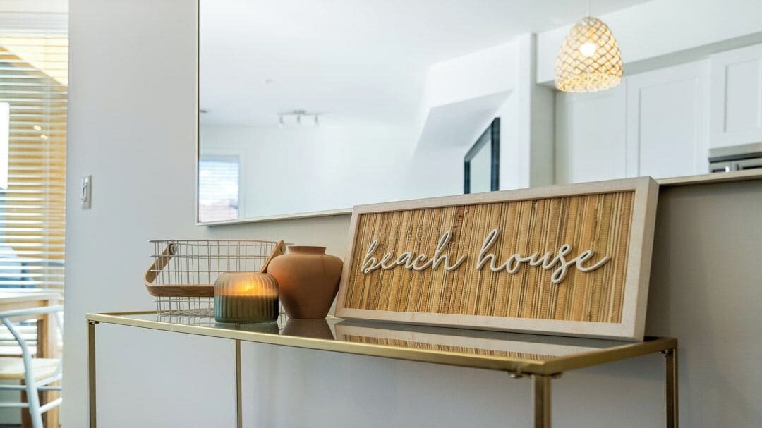 A modern interior with a framed sign that reads "bichen house" on a gold table.