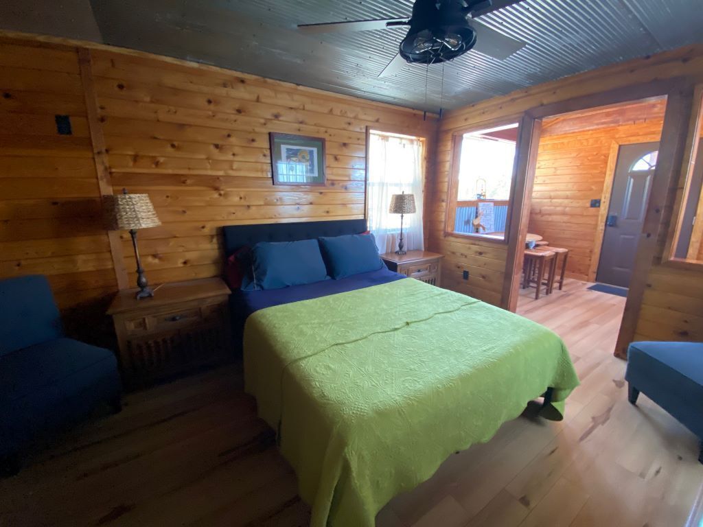 Une chambre à coucher dans un chalet en bois, avec un lit, une table de chevet, une lampe et une fenêtre.