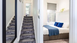 A bedroom with a bed, a window, and a staircase. - Stylish Hideaway Flat at Milton Park Highgate (London)
