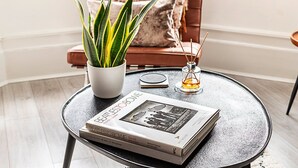 A round table with a book titled 'BEATLES TO BOWIE', a potted plant, and a candle holder. - Stylish Hideaway Flat at Milton Park Highgate (London)