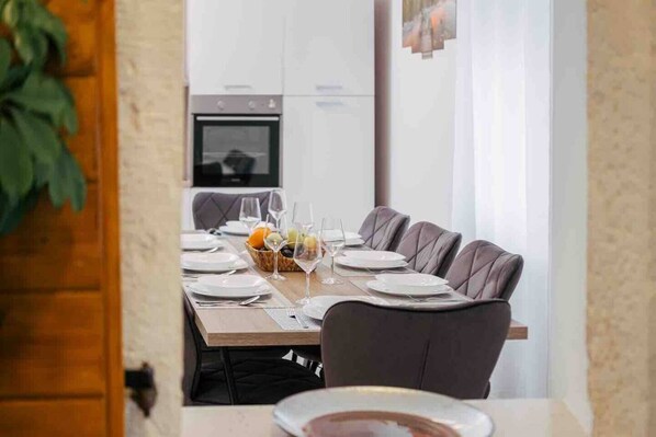 A dining area with a table set for six, including plates, glasses, and a fruit basket.