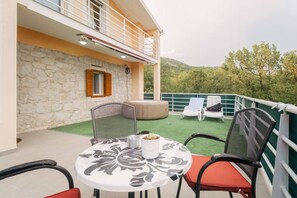 A balcony with a table, chairs, and a hot tub.