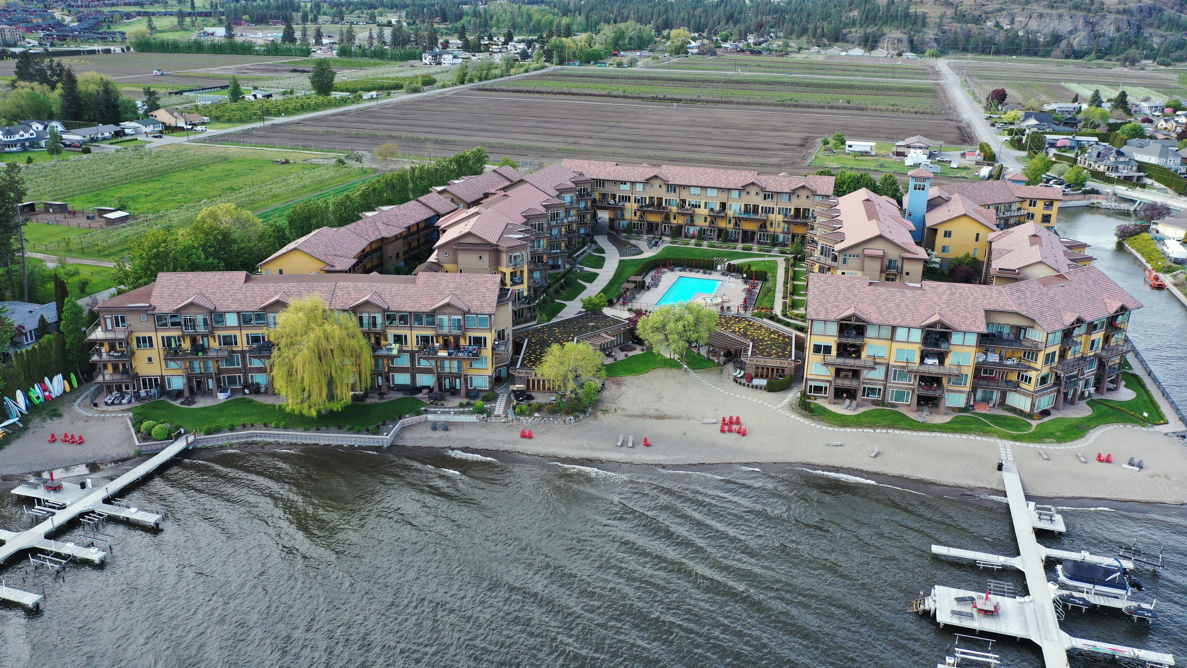 Un hôtel à plusieurs étages doté d’une piscine, situé près d’une rivière où se trouvent des quais.
