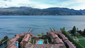 Een hotel met een zwembad, een steiger en uitzicht op een meer en bergen.