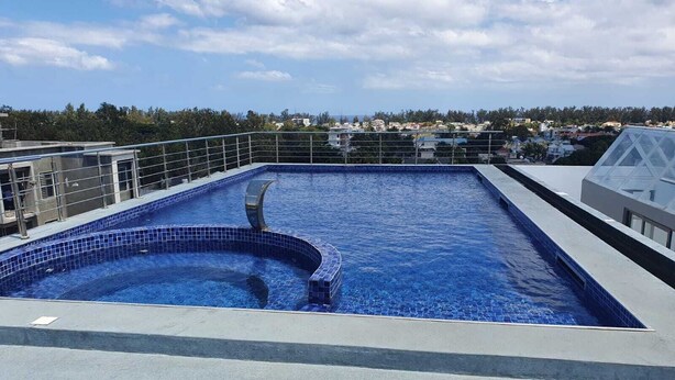 A rooftop swimming pool with a clear view of the surrounding buildings and landscape. - Peaceful and beautiful space to spend quality time
close to beach  (Flic en Flac)