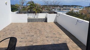A rooftop terrace with stone flooring, a black chair, and a view of the surrounding neighborhood. - Peaceful and beautiful space to spend quality time
close to beach  (Flic en Flac)