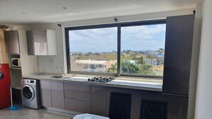 A modern kitchen with a large window, stainless steel appliances, and a dining area with a glass table. - Peaceful and beautiful space to spend quality time
close to beach  (Flic en Flac)