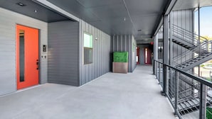 Un couloir moderne avec une porte rouge, des murs gris et un escalier sur le côté droit.