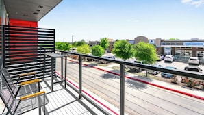 Un balcon avec des balustrades en métal donnant sur un parking et un immeuble sur lequel on peut lire l’inscription « ELECT DERMATOLOGY ».