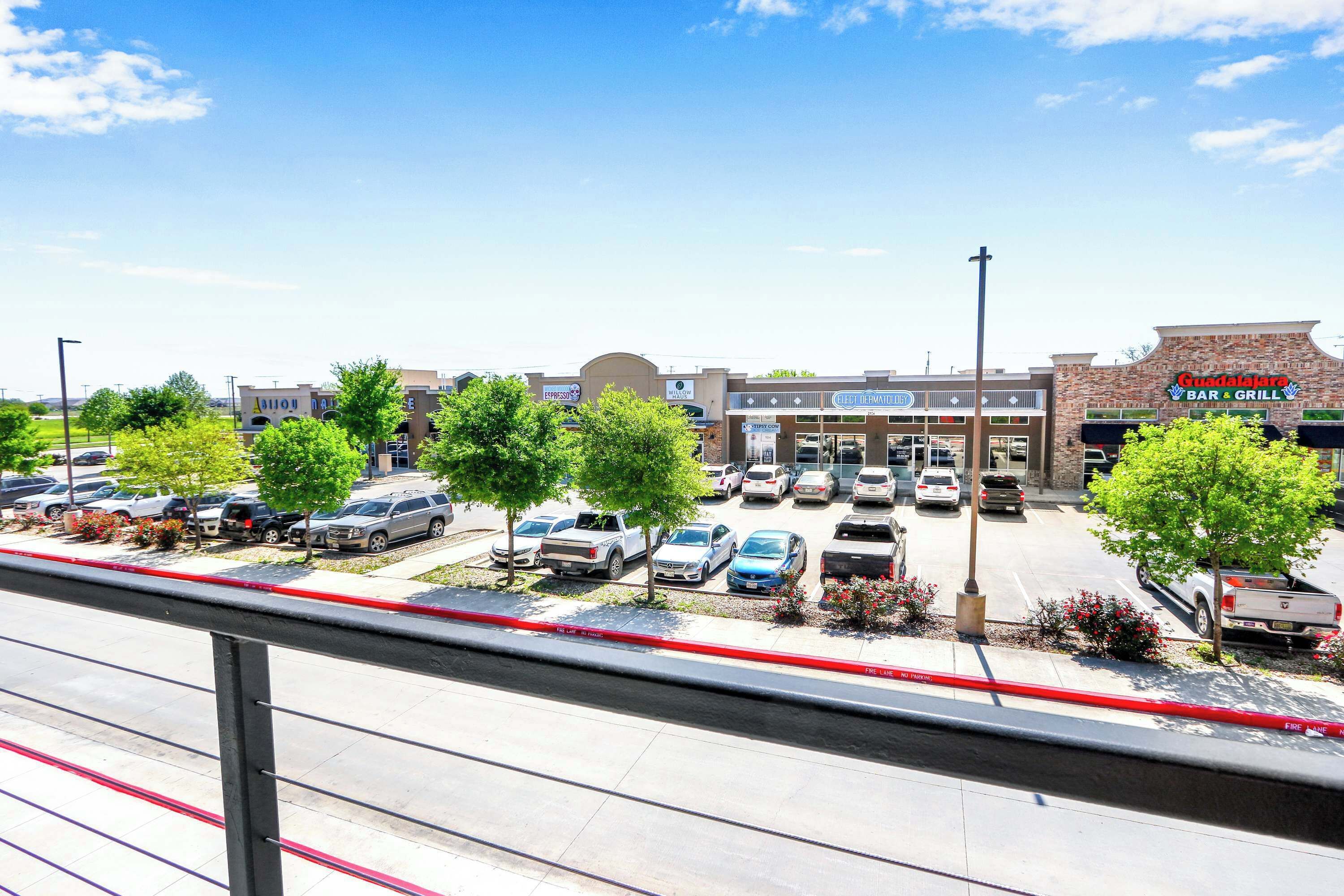 A commercial area with a parking lot, a restaurant named 'Guadalajara Bar & Grill,' and a building with a sign for 'Elect Dermatology.'